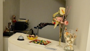 A bathroom with a white countertop, a glass vase with seashells, a small decorative item, and a box of chocolates. - Caudullo (Letojanni)