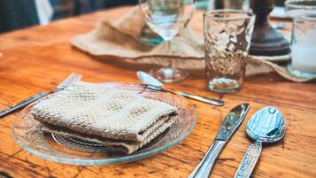 Una mesa de madera dispuesta con un mantel doblado, un plato de vidrio, cubiertos y un candelabro.