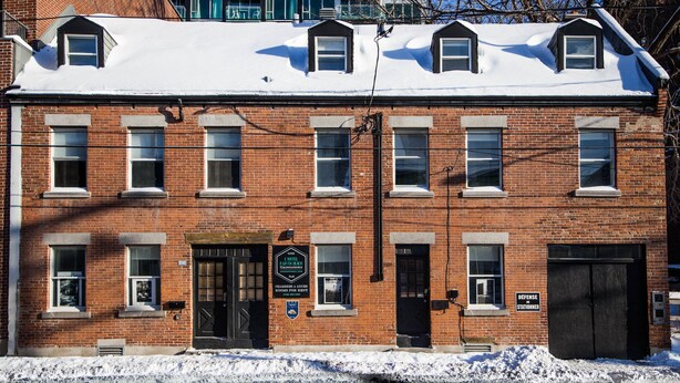 A red brick building with multiple windows and a snow-covered roof. - HPG Griffintown (Montreal)