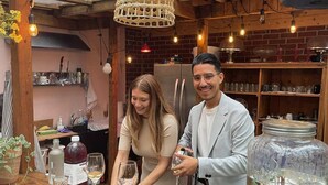 A rustic kitchen with wooden beams, a brick wall, and a wooden bar area with wine glasses and a large jar. - HPG Griffintown (Montreal)
