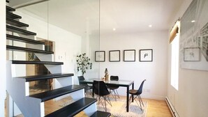 A modern interior with a staircase, dining area, and artwork on the walls. - HPG Griffintown (Montreal)