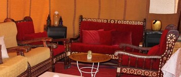 Una habitación tradicional con un sofá rojo, sillones de madera y una mesita redonda.