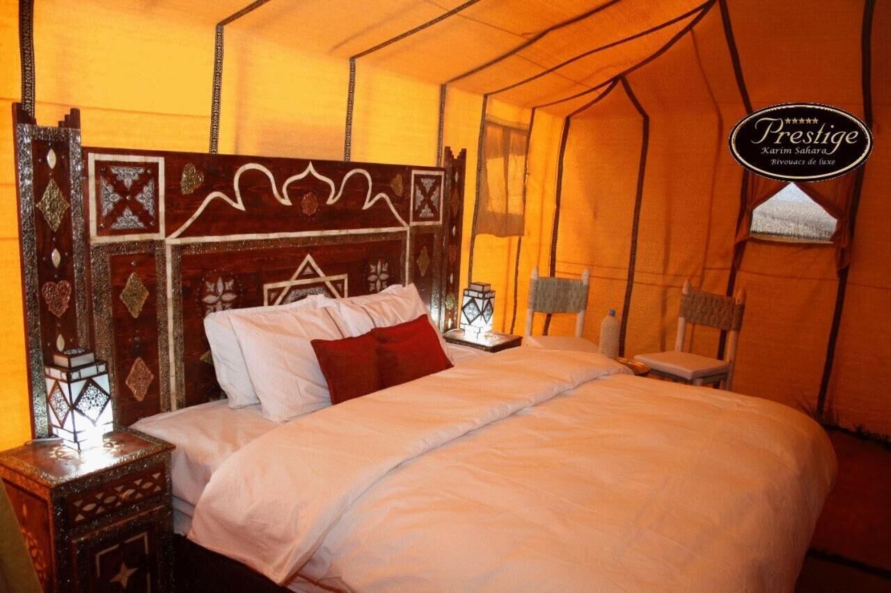 A tent-style room with a bed, a nightstand, and a chair.