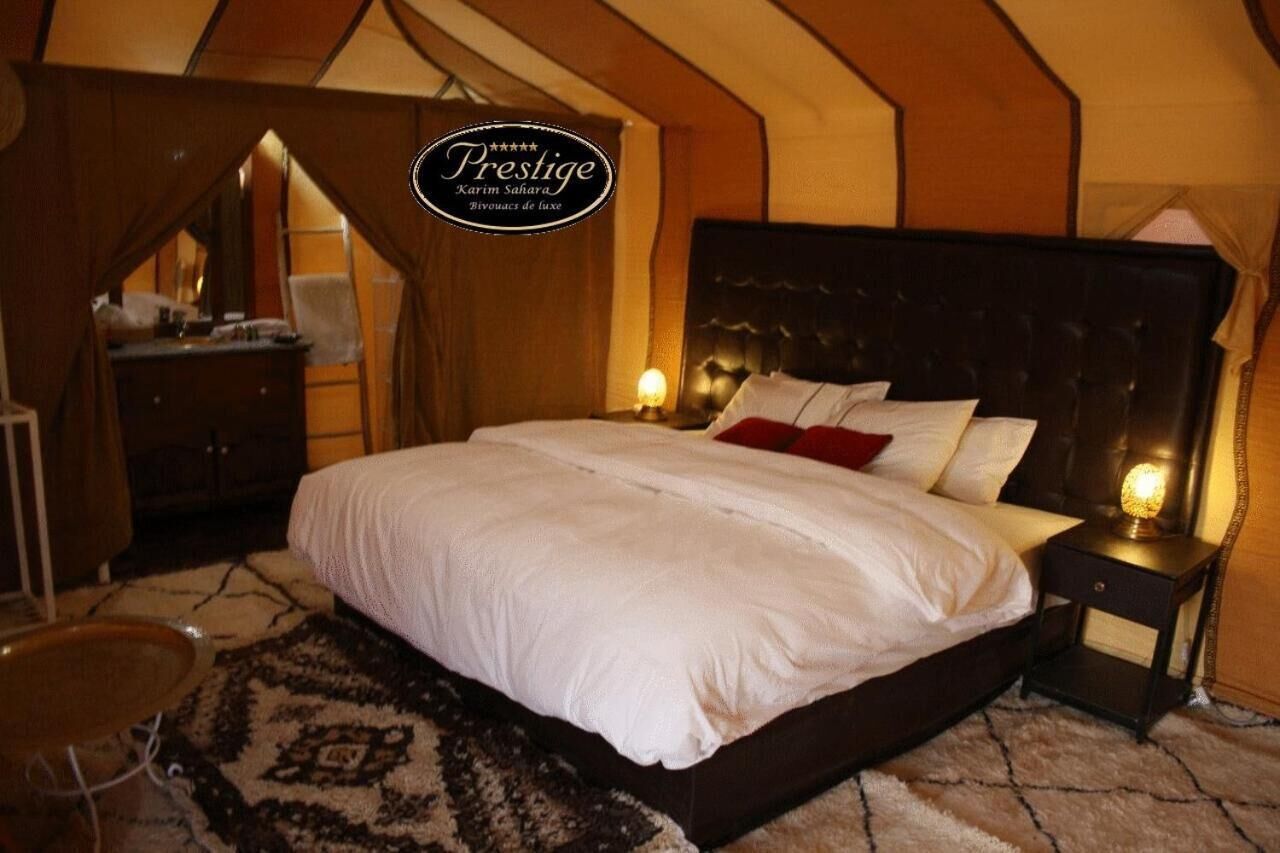 A bedroom with a large bed, a nightstand, and a desk with a chair.