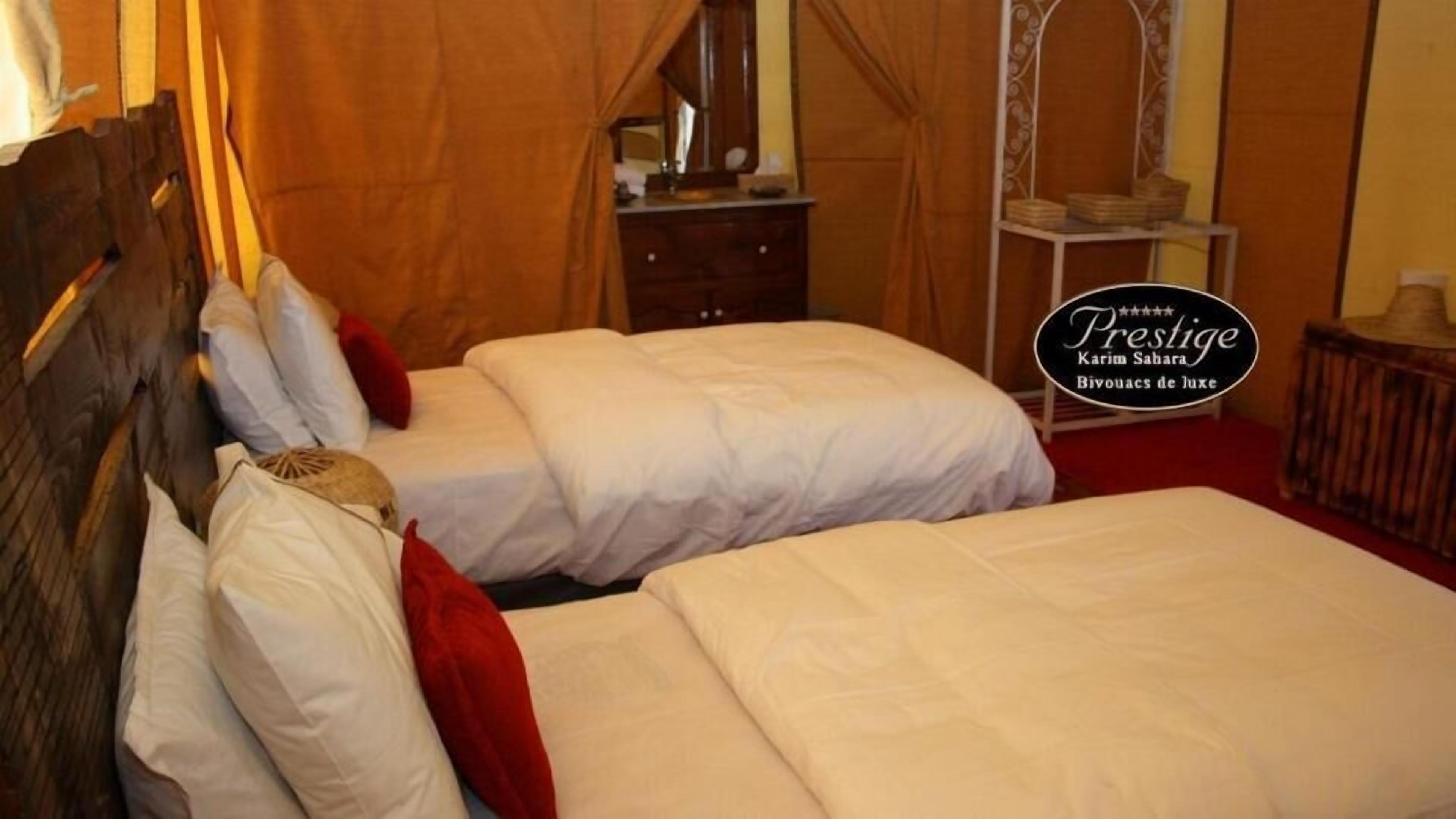 Een hotelkamer met twee bedden, een houten hoofdbord, een spiegel en een tafeltje met een lamp.