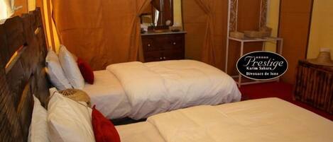 Een hotelkamer met twee bedden, een houten hoofdbord, een spiegel en een tafeltje met een lamp.