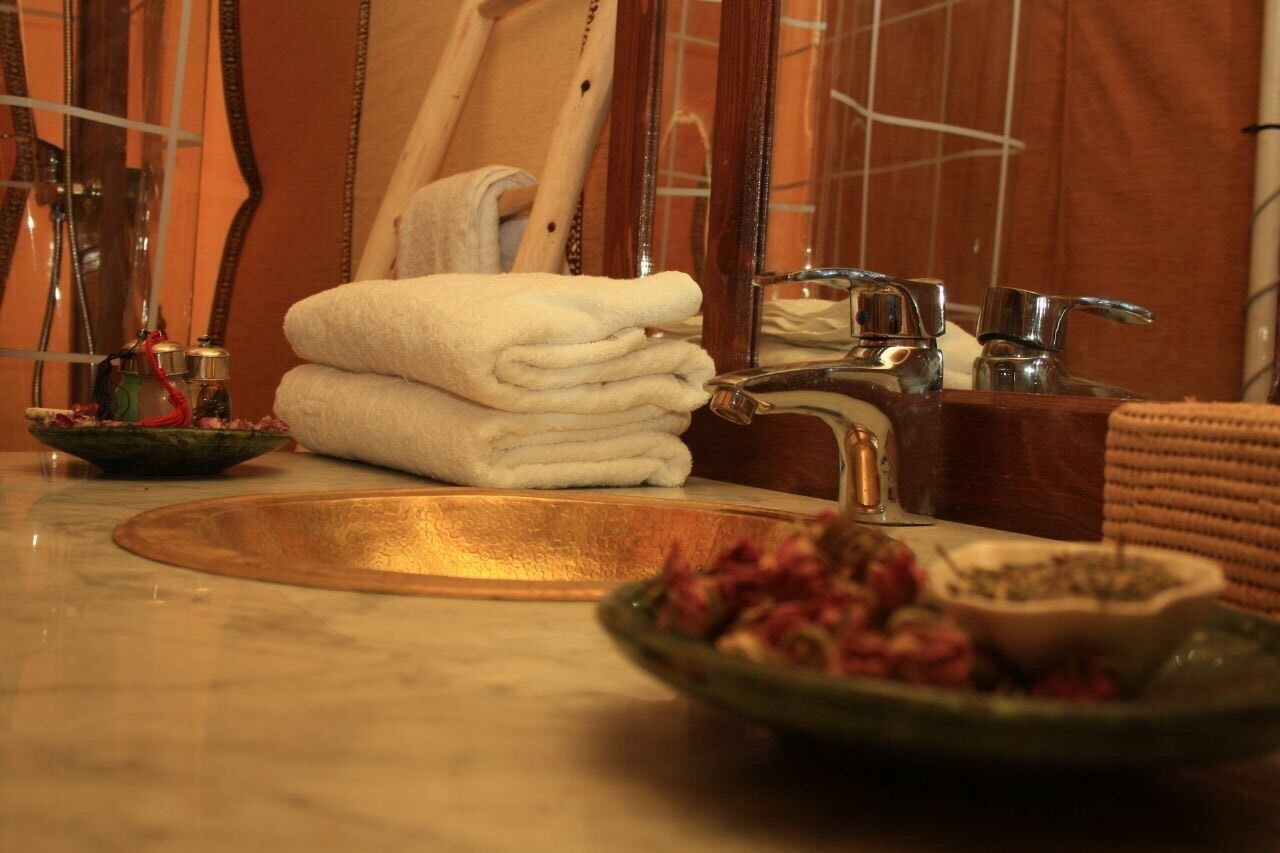 A bathroom with a marble sink, a mirror, a towel rack, and a bowl of flowers.