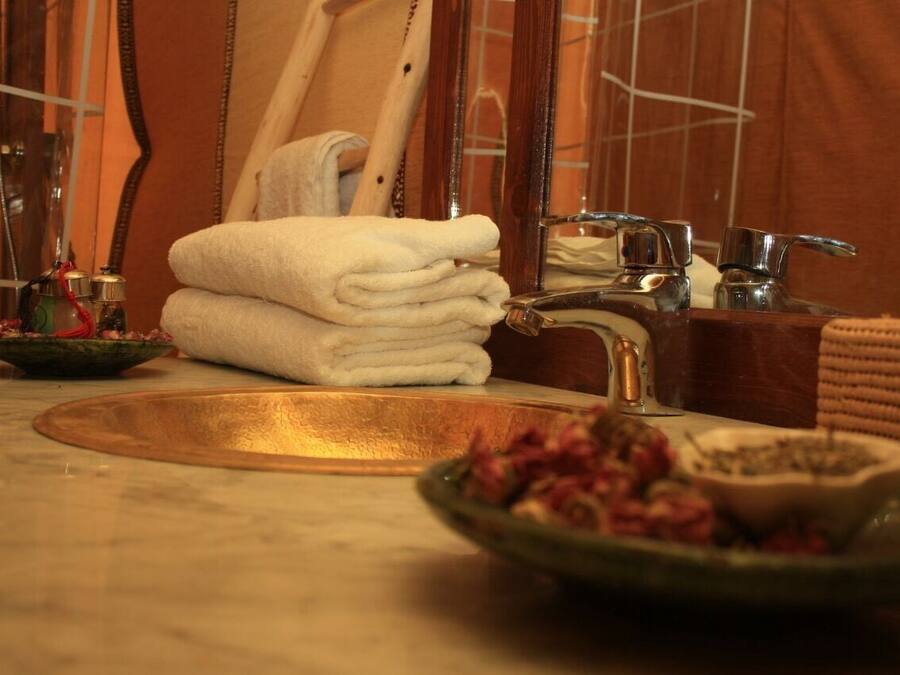 A bathroom with a marble sink, a mirror, a towel rack, and a bowl of flowers.