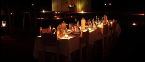 Un área de comedor al aire libre con mesas dispuestas para una comida, velas y vistas al agua.