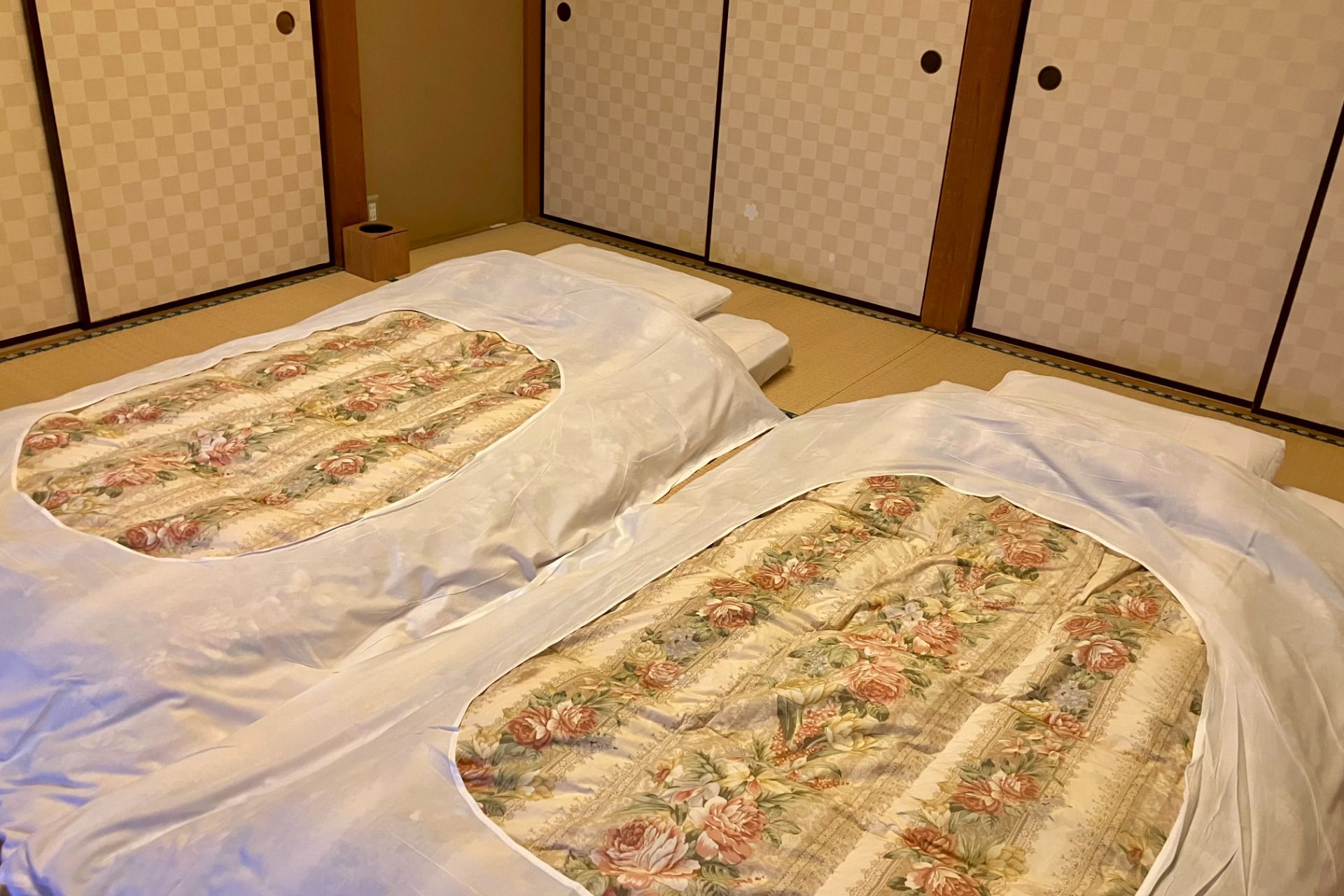 Two beds with floral bedding in a room with traditional Japanese sliding doors.