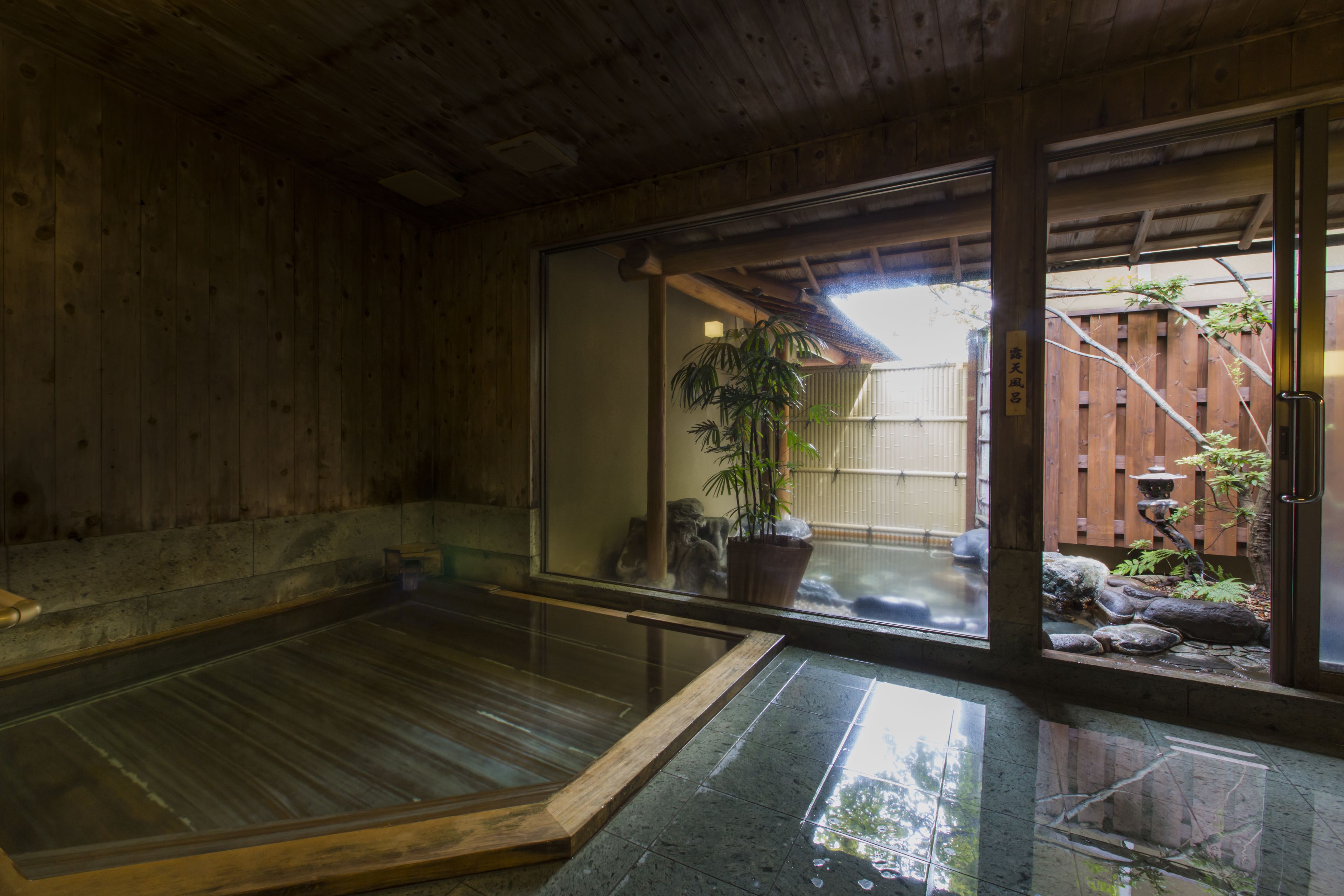 A traditional Japanese onsen with a wooden interior and a view of a garden outside.