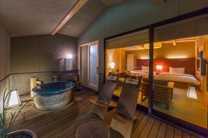 A hotel room with a large bathtub, a bed with a red headboard, and a glass door leading to a balcony. - Izu Ito Hot Springs Toushinan Komeya-Kyoritsu Resort (Ito)