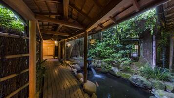 Stroll through a serene garden pathway lined with wooden beams, leading to a soothing waterfall.