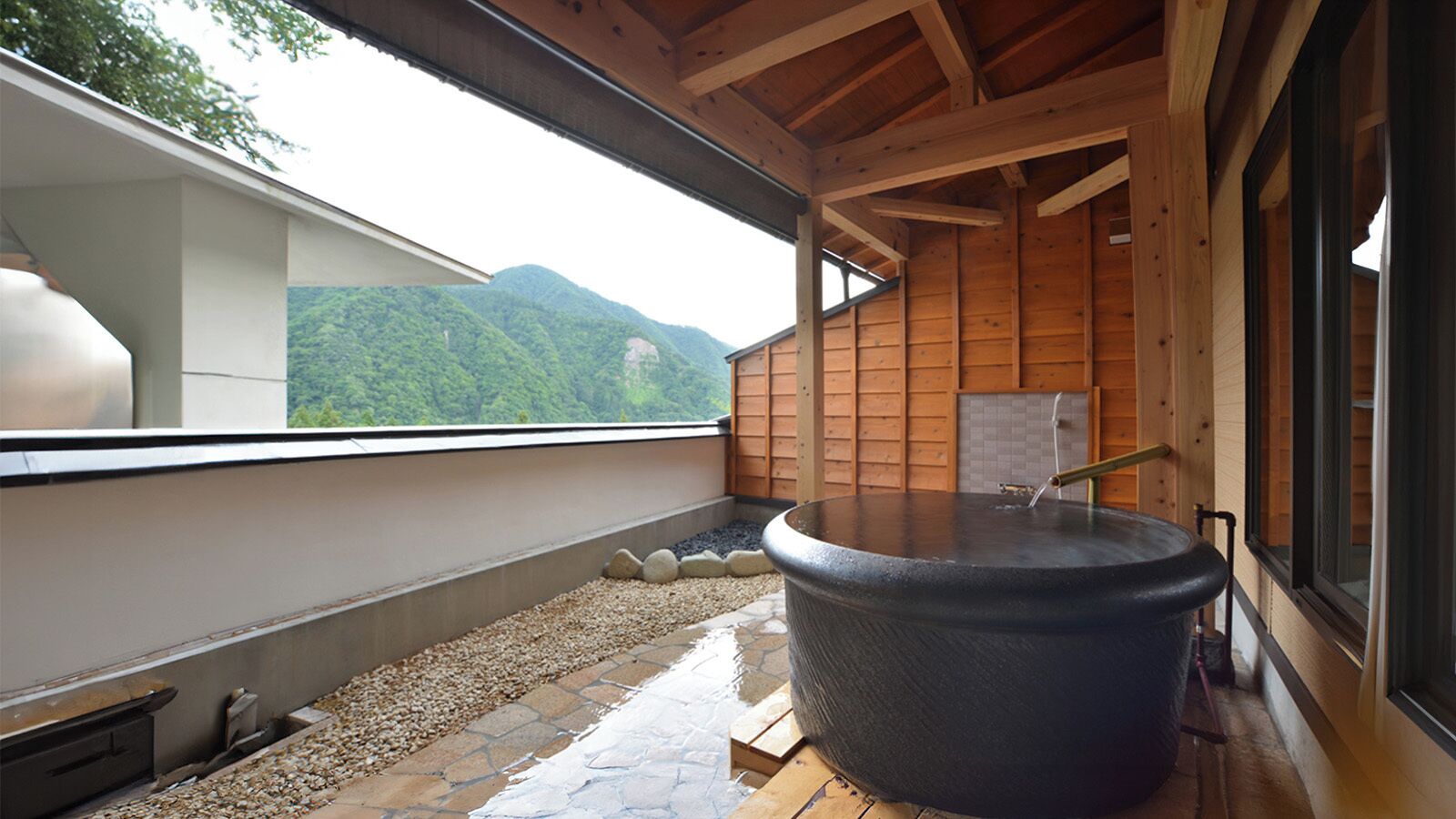 Un jacuzzi en una terraza de madera con vistas a montañas.