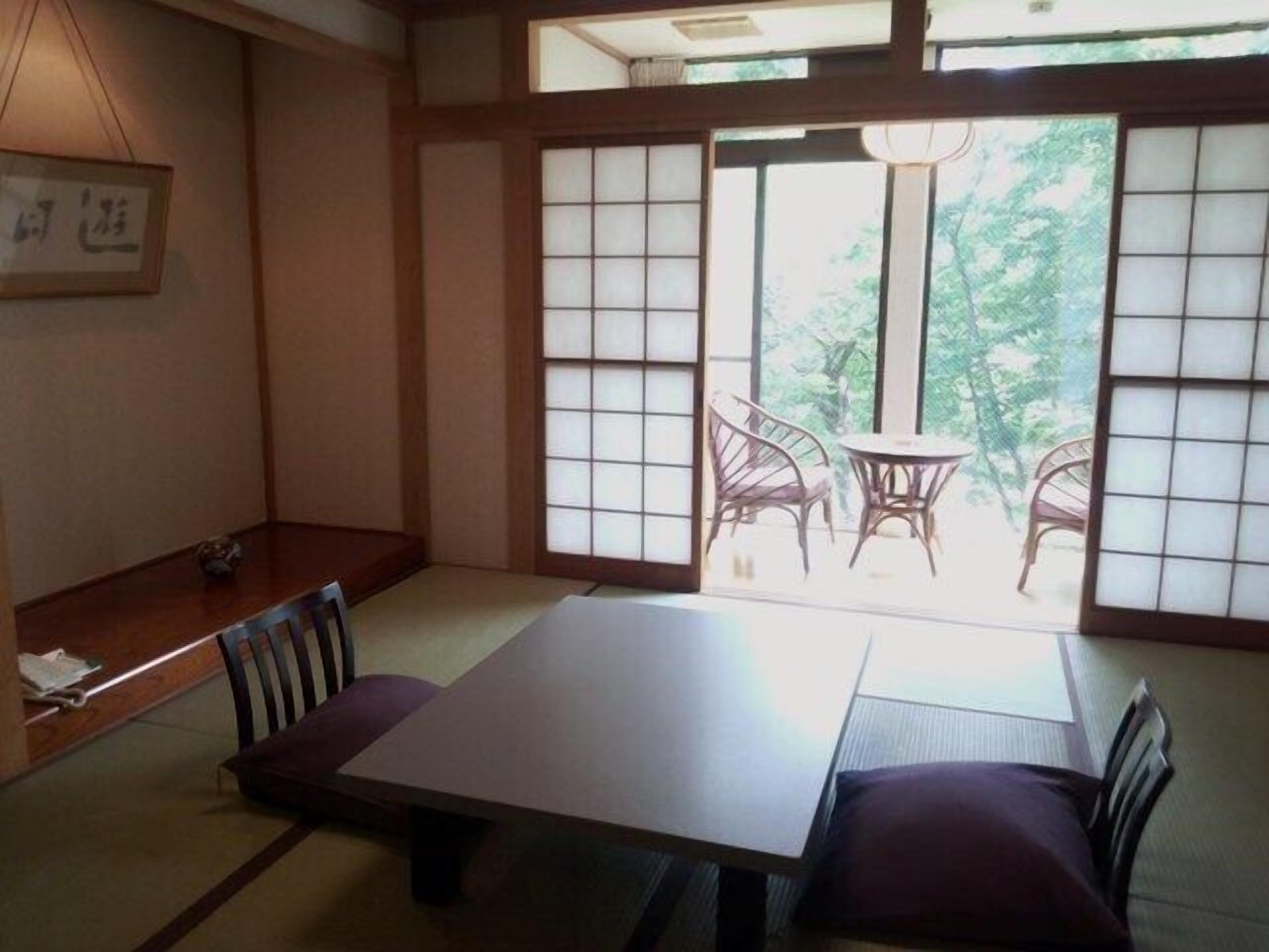 Ein traditioneller japanischer Raum mit Tatami-Böden, einem niedrigen Tisch und Shoji-Schiebetüren.