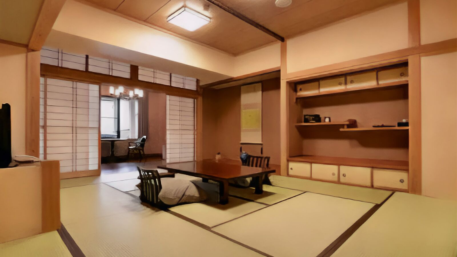 Ein Raum mit Tatami-Matten, einem niedrigen Tisch, Stühlen, einem Schrank und einer Schiebetür.