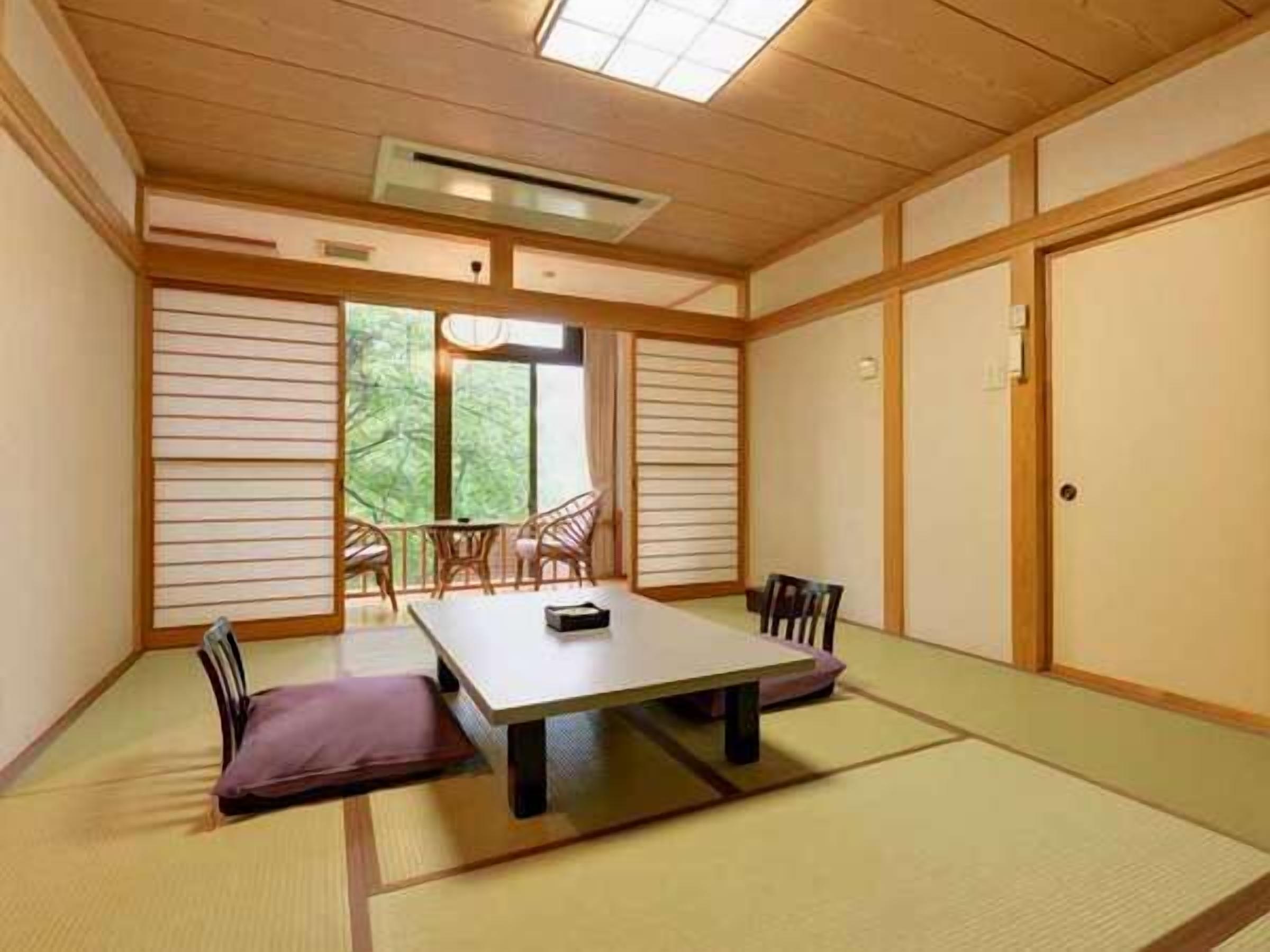 Una habitación japonesa tradicional con suelo de tatami, una mesa baja y puertas correderas.