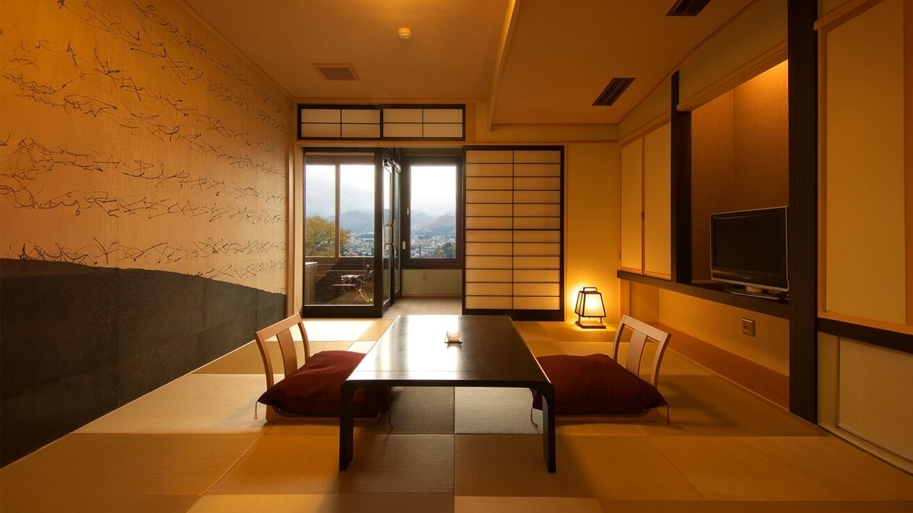 Ein traditioneller japanischer Raum mit Tatami-Böden, einem niedrigen Tisch und einem Fernseher auf einem Standfuß.