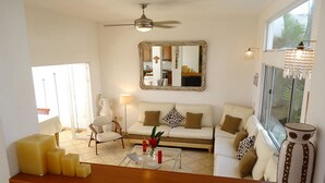 A living room with a sofa, armchairs, a coffee table, a mirror, and a window with a view.