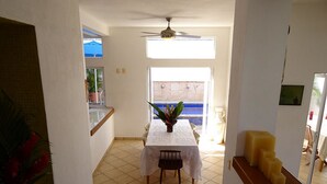 A dining area with a table and chairs, a ceiling fan, and a view of the outside.