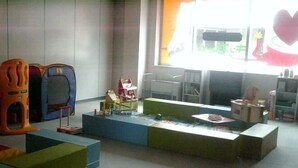 Ein Kinderspielbereich mit bunten Spielgeräten und einem großen Fenster mit Blick auf ein Gebäude.