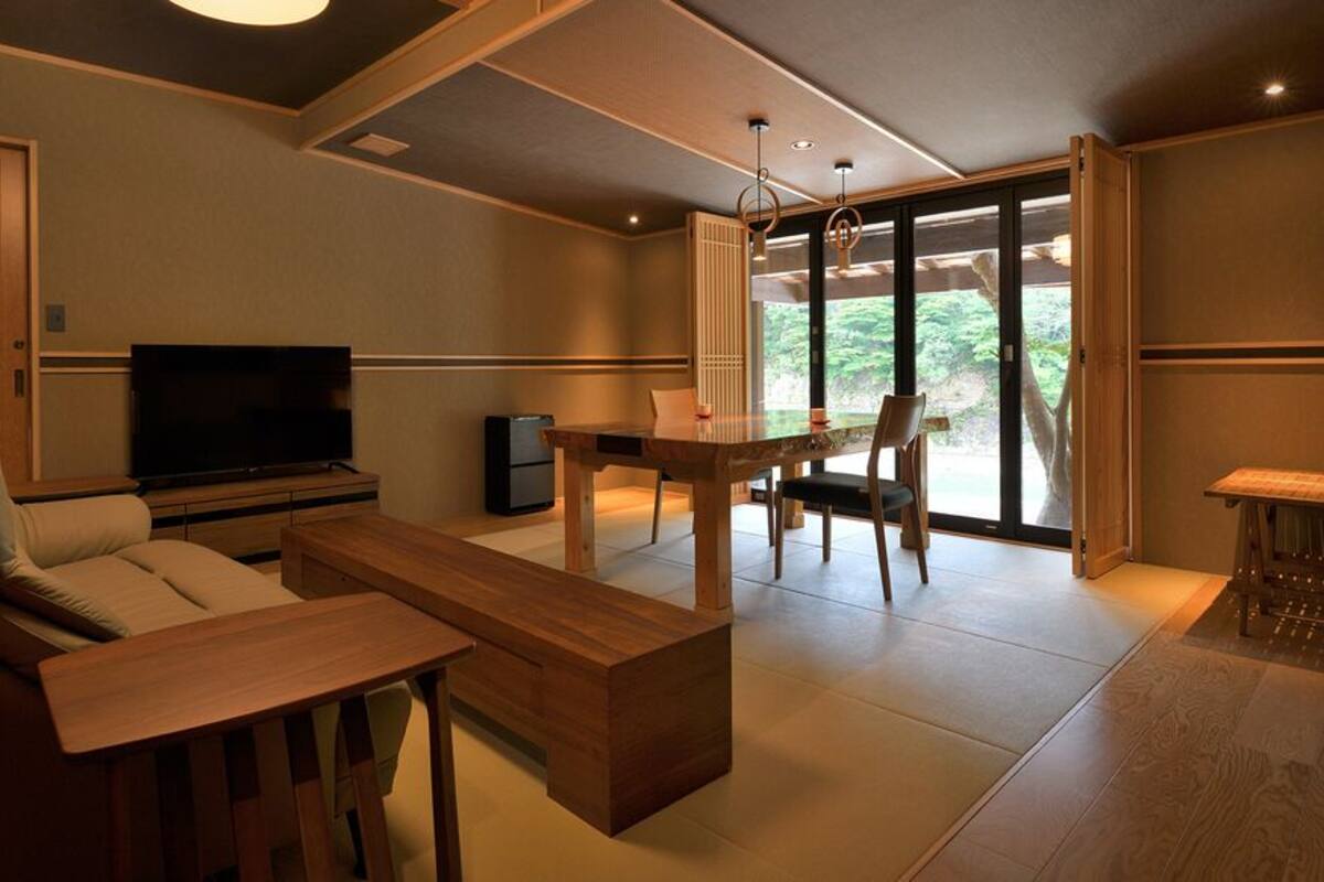 Una sala de estar moderna con un sofá, una mesa de centro, un televisor y un comedor con sillas.