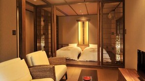 A traditional Japanese-style room with tatami flooring, a low wooden table, and a sofa. - Shikinosato Kikuya (Sekikawa)