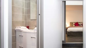 Un baño moderno con cabina de ducha de vidrio, un tocador blanco con cajones y un espejo grande.