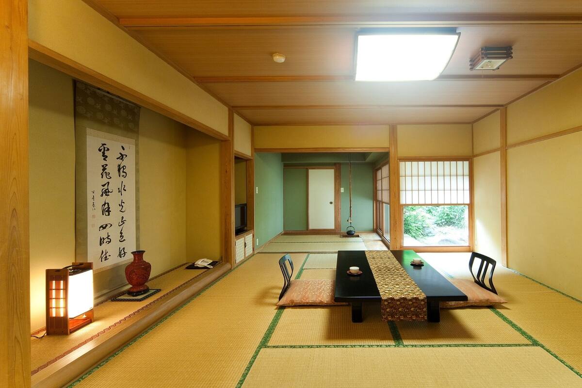 Una habitación japonesa tradicional con suelo de tatami, una mesa baja y puertas correderas.