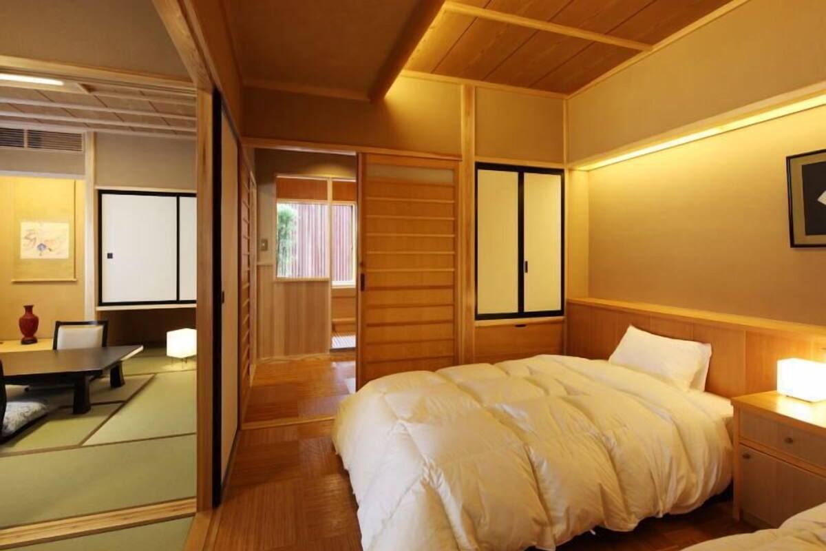 Un dormitorio de estilo japonés tradicional con cama, mesita de noche y puertas correderas.