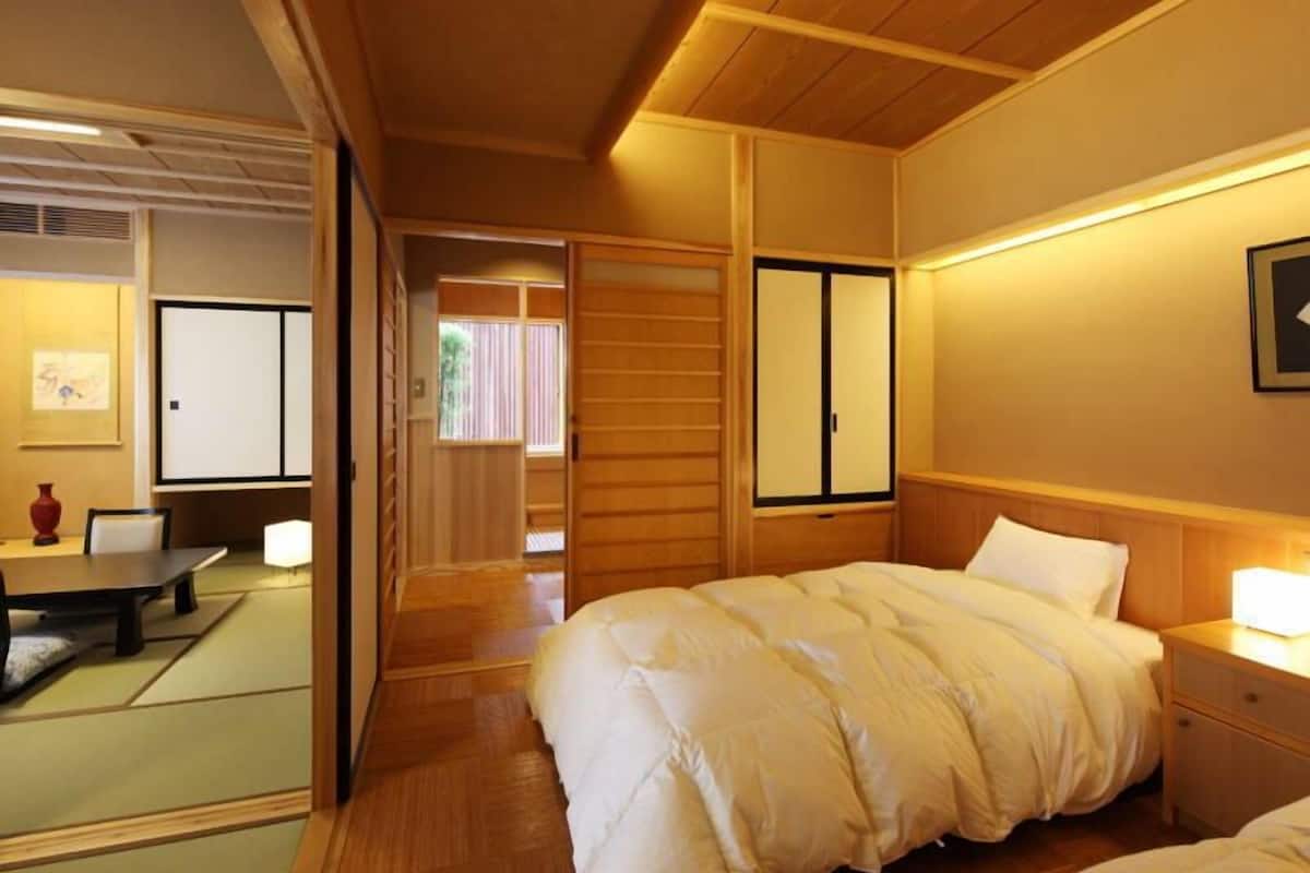Ein traditionell japanisch gestaltetes Schlafzimmer mit Bett, Nachttisch und Schiebetüren.