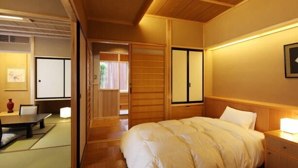 Quarto japonês tradicional com cama, mesa de cabeceira e portas deslizantes.
