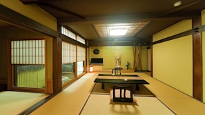 A traditional Japanese room with tatami flooring, a low table, a television, and sliding doors.