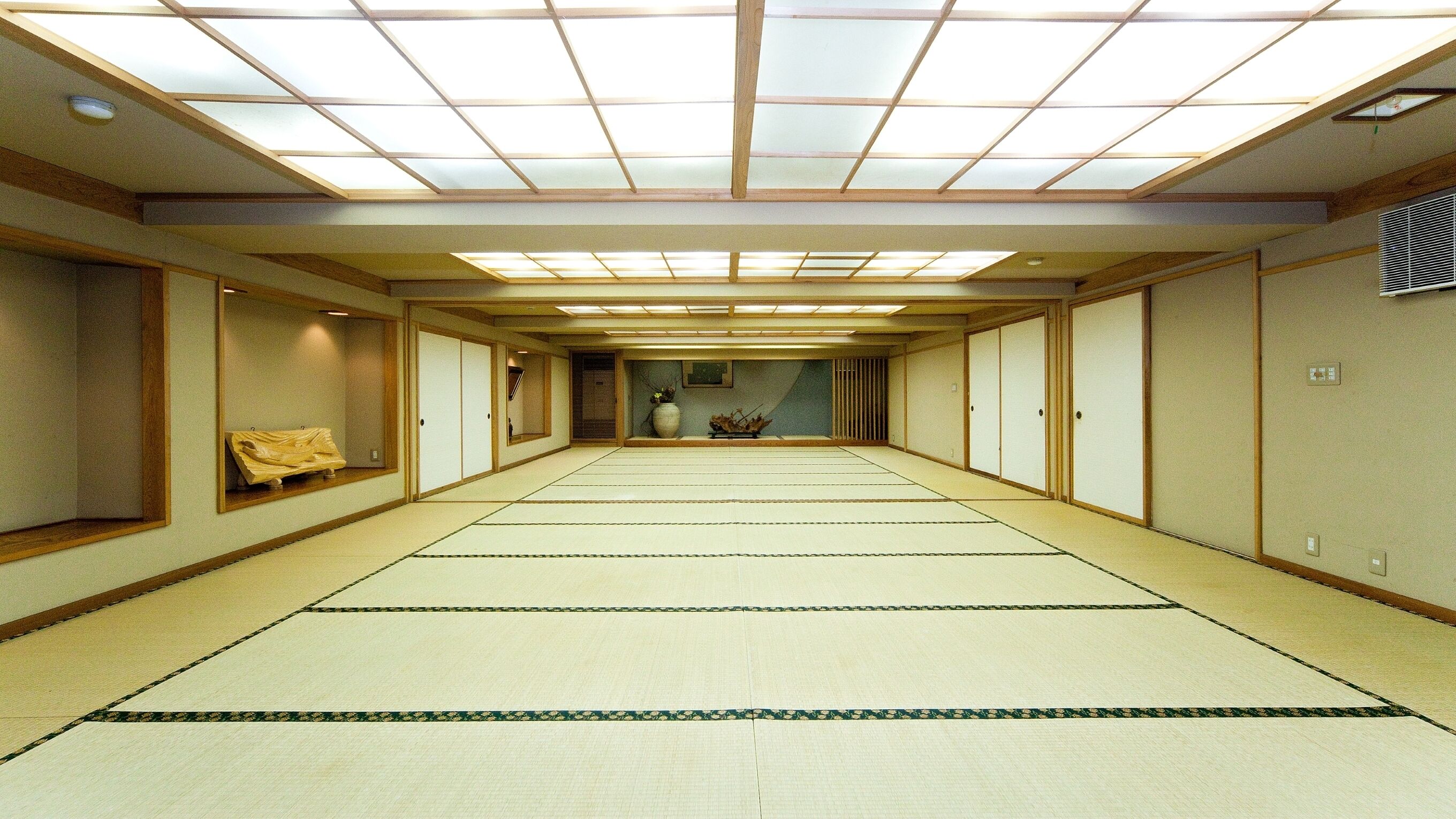 Una habitación japonesa tradicional con suelo de tatami, puertas correderas y tragaluces.