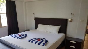 A hotel room with a large bed, a bedside table, and a bench at the foot of the bed. - Hibiscus Tabua Villas (Nadi)