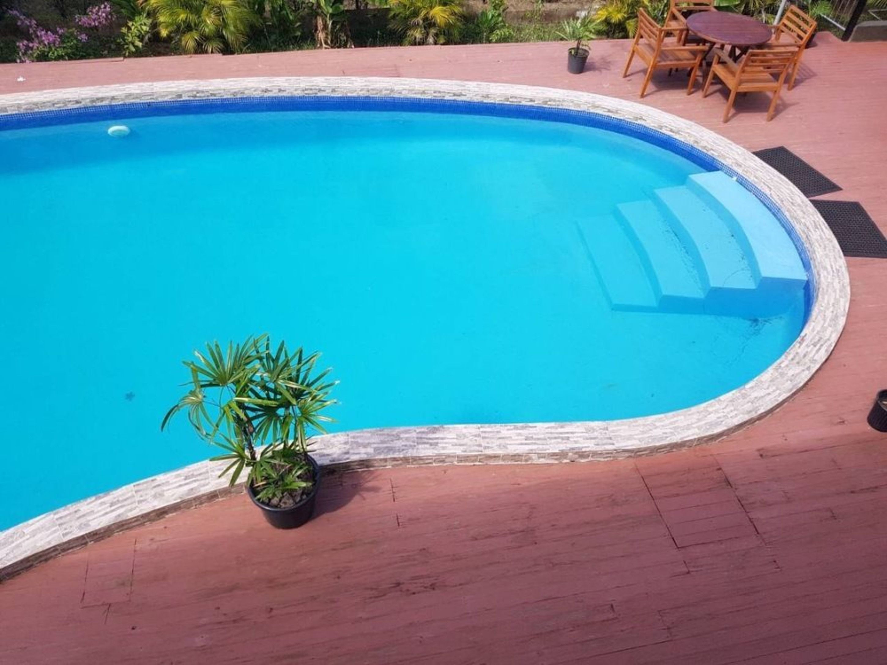A swimming pool with a wooden deck and a table with chairs.