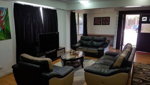 A living room with a sofa set, a coffee table, a flat-screen TV, and artwork on the walls. - Hibiscus Tabua Villas (Nadi)