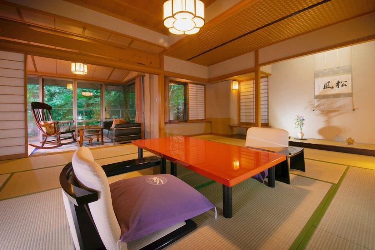 Una habitación tradicional japonesa con suelo de tatami, una mesa baja y un sofá.