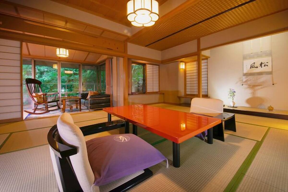 Una habitación tradicional japonesa con suelo de tatami, una mesa baja y un sofá.