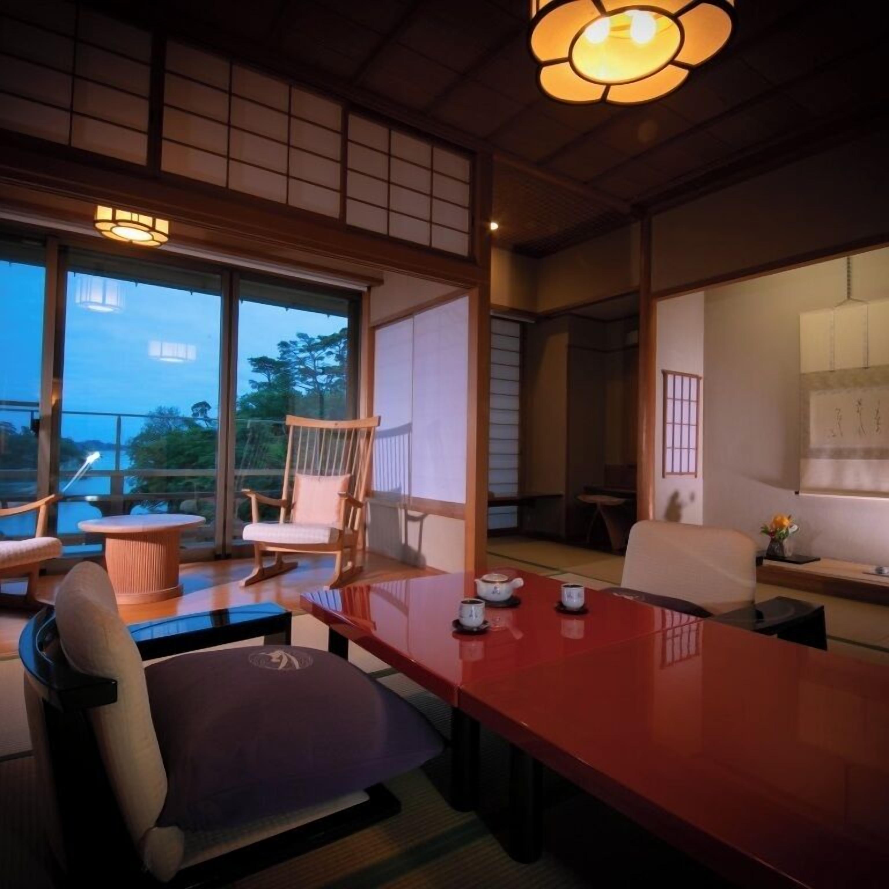 Una habitación tradicional japonesa con suelo de tatami, una mesa baja y una silla de madera.
