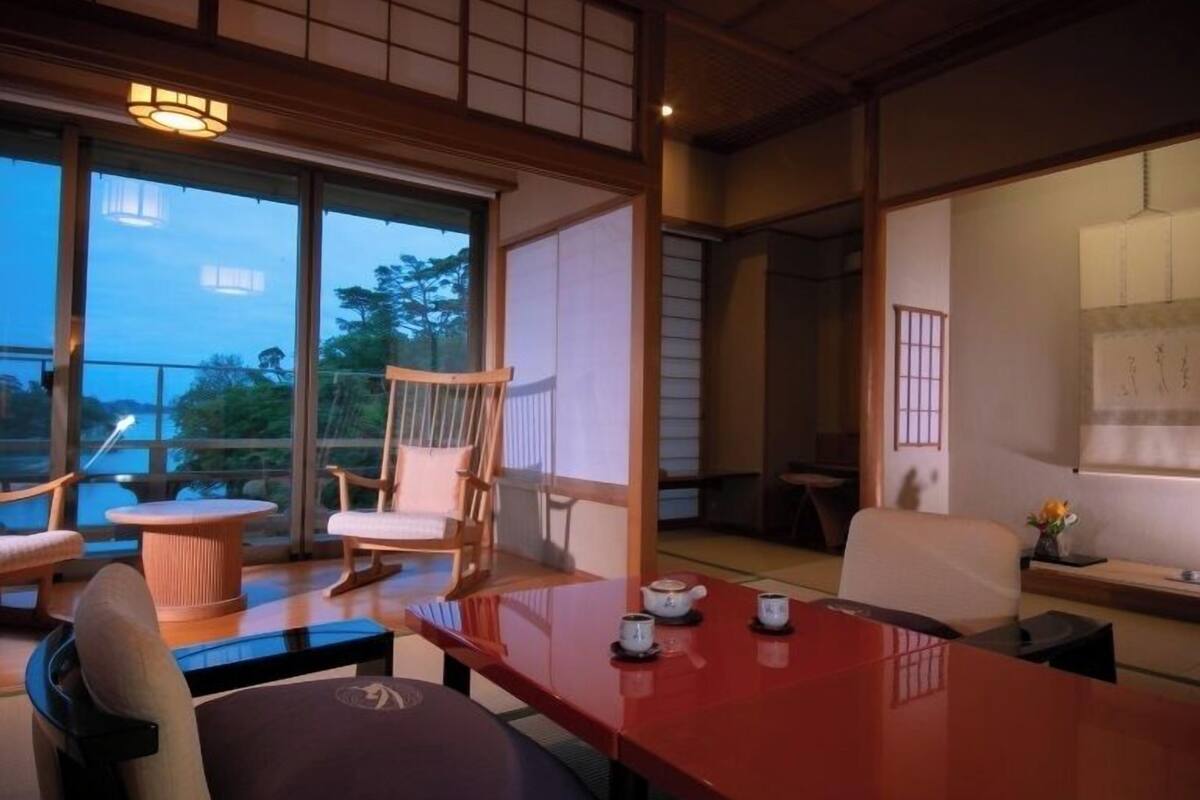 Una habitación tradicional japonesa con suelo de tatami, una mesa baja y una silla de madera.