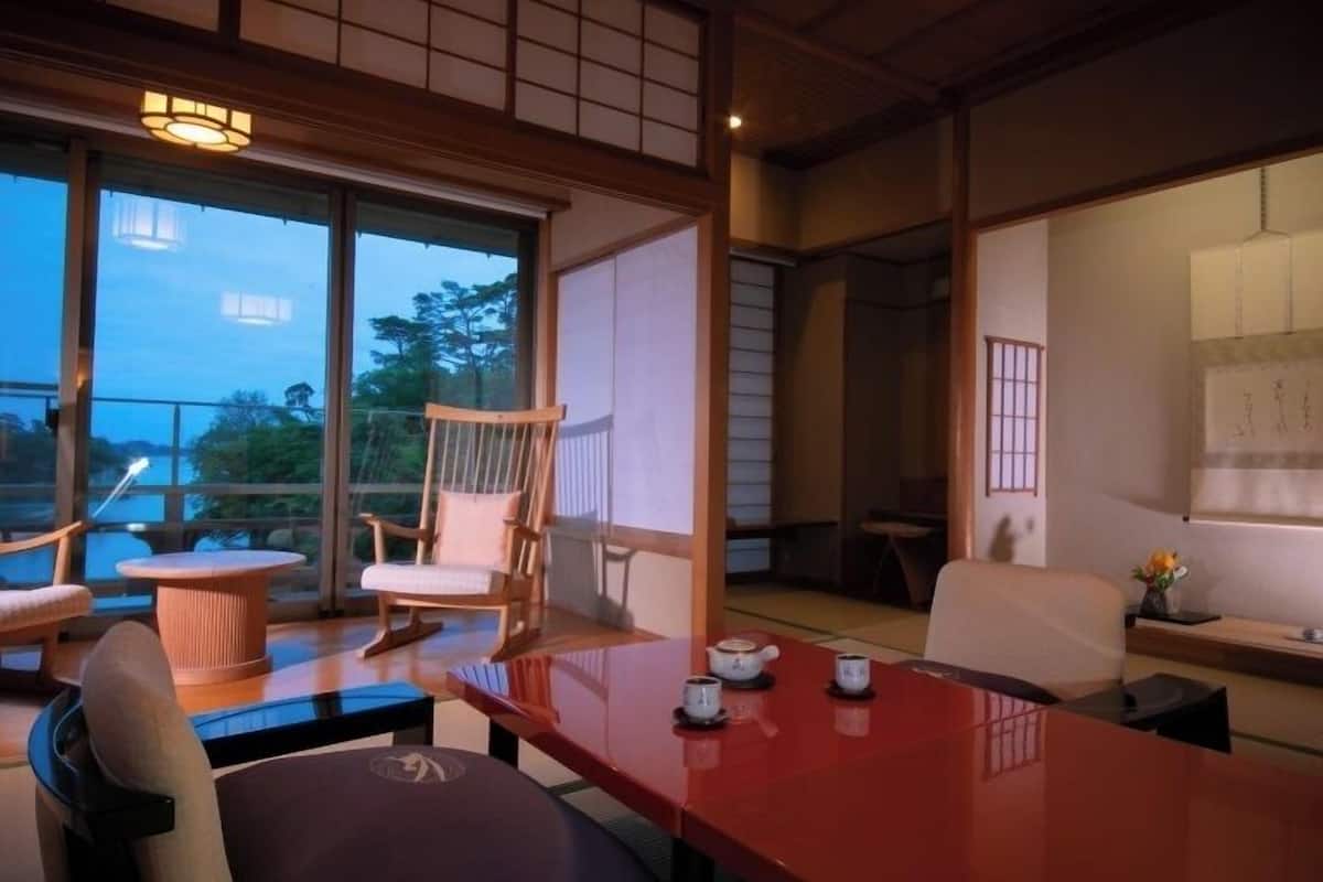 Una habitación tradicional japonesa con suelo de tatami, una mesa baja y una silla de madera.
