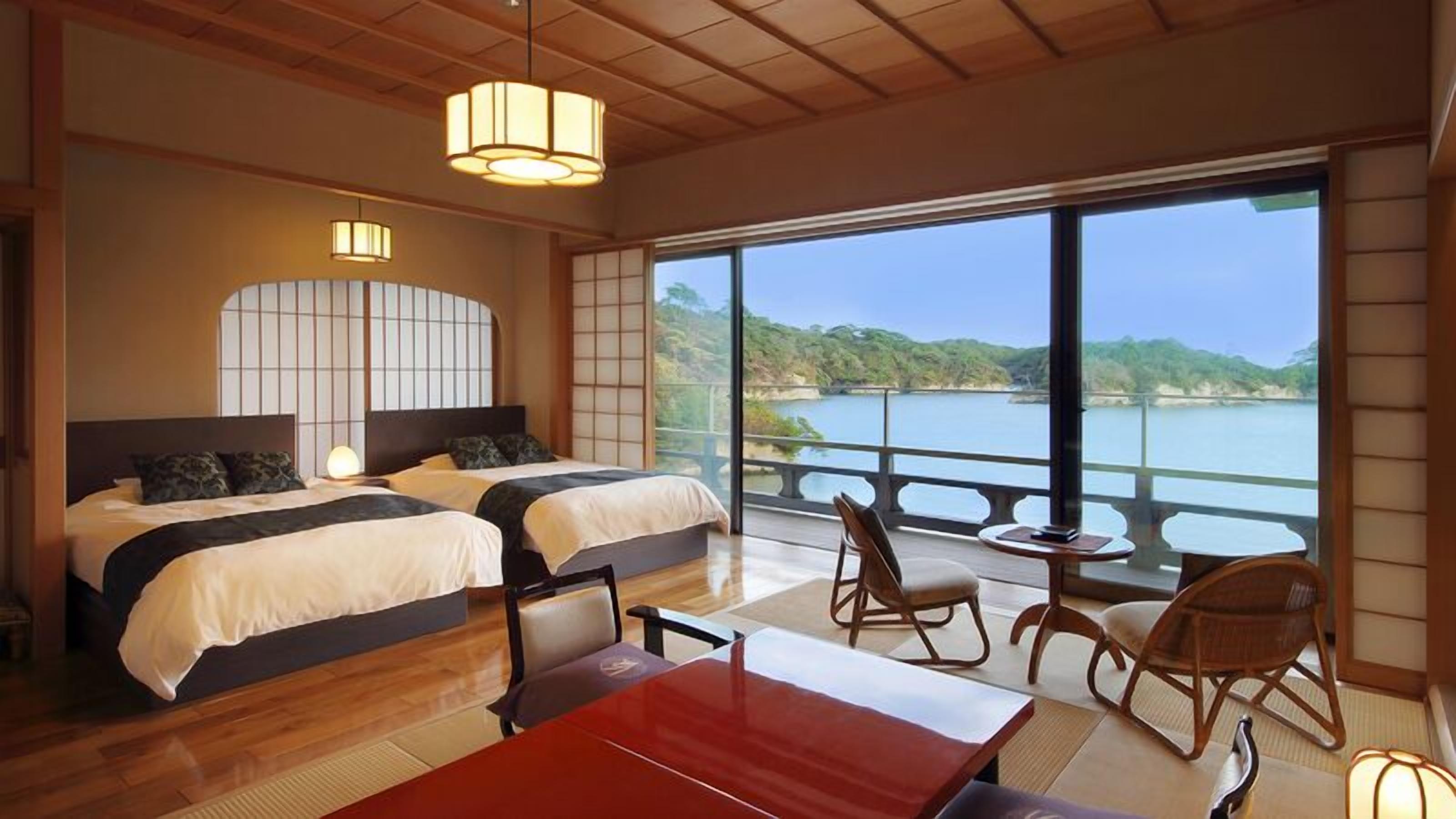 Habitación de hotel con dos camas, una mesa de comedor, sillas, vista a un lago y un balcón.