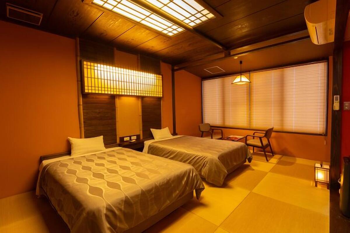 A hotel room with two beds, a desk, and a chair.
