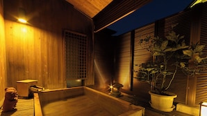 Un espacio tipo spa de madera con un jacuzzi, una mesita y una planta en maceta.