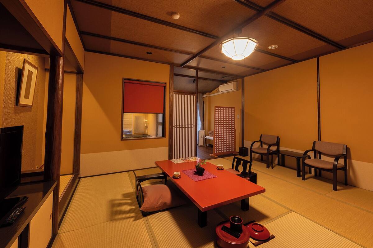 A traditional Japanese room with tatami flooring, a low table with cushions, and a sliding door.