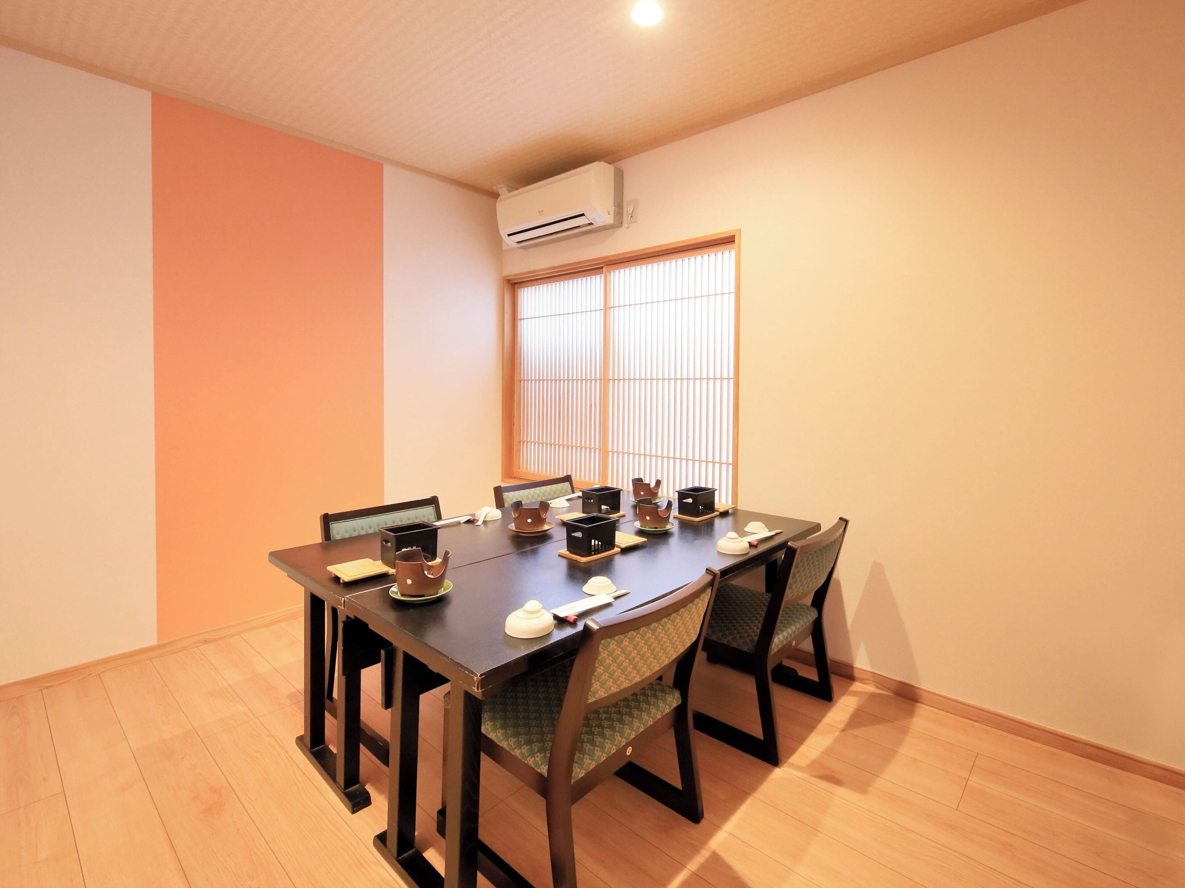 Un coin repas avec une table en bois, six chaises et une fenêtre de style japonais traditionnel.