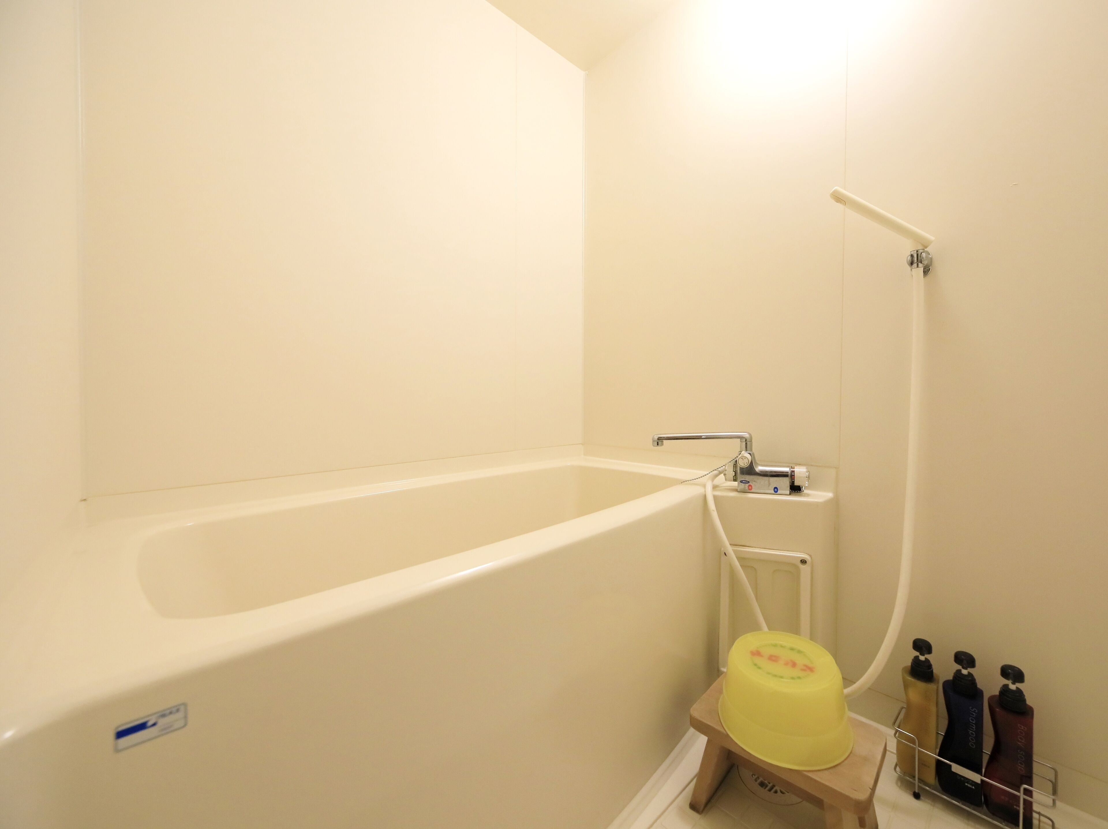 A bathroom with a bathtub, a shower, and a small stool with toiletries.