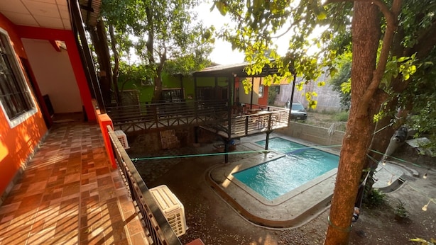 Una piscina rodeada por una zona techada con suelo de baldosas y una pequeña mesa.