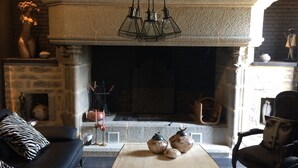 Una sala de estar moderna con chimenea de piedra, un sofá de cuero negro, una mesa de centro de madera y un sillón negro.